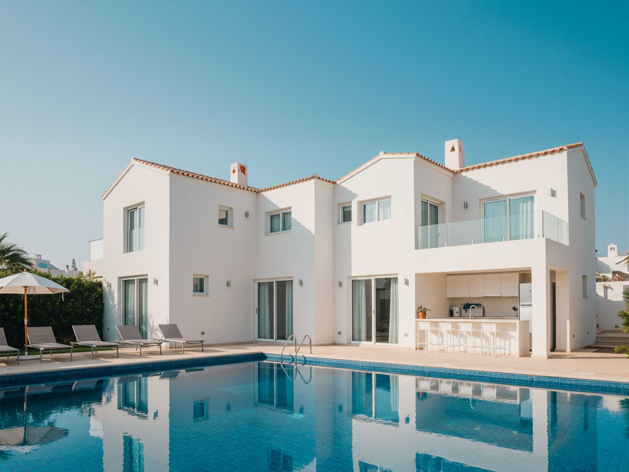 青空の下に建つモダンなヴィラとプール
