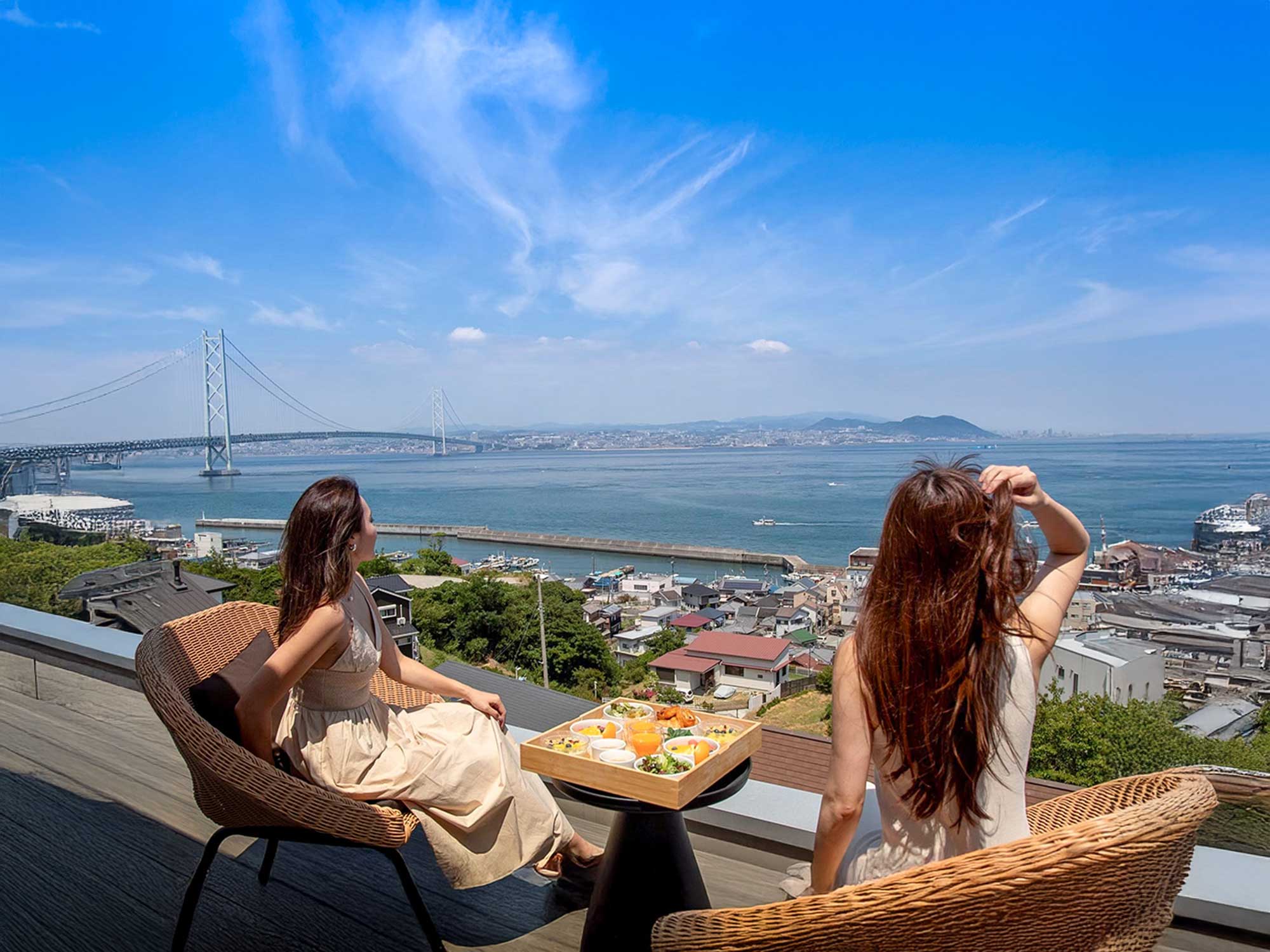 淡路島のテラスで明石海峡大橋を眺めながら食事を楽しむ女性二人
