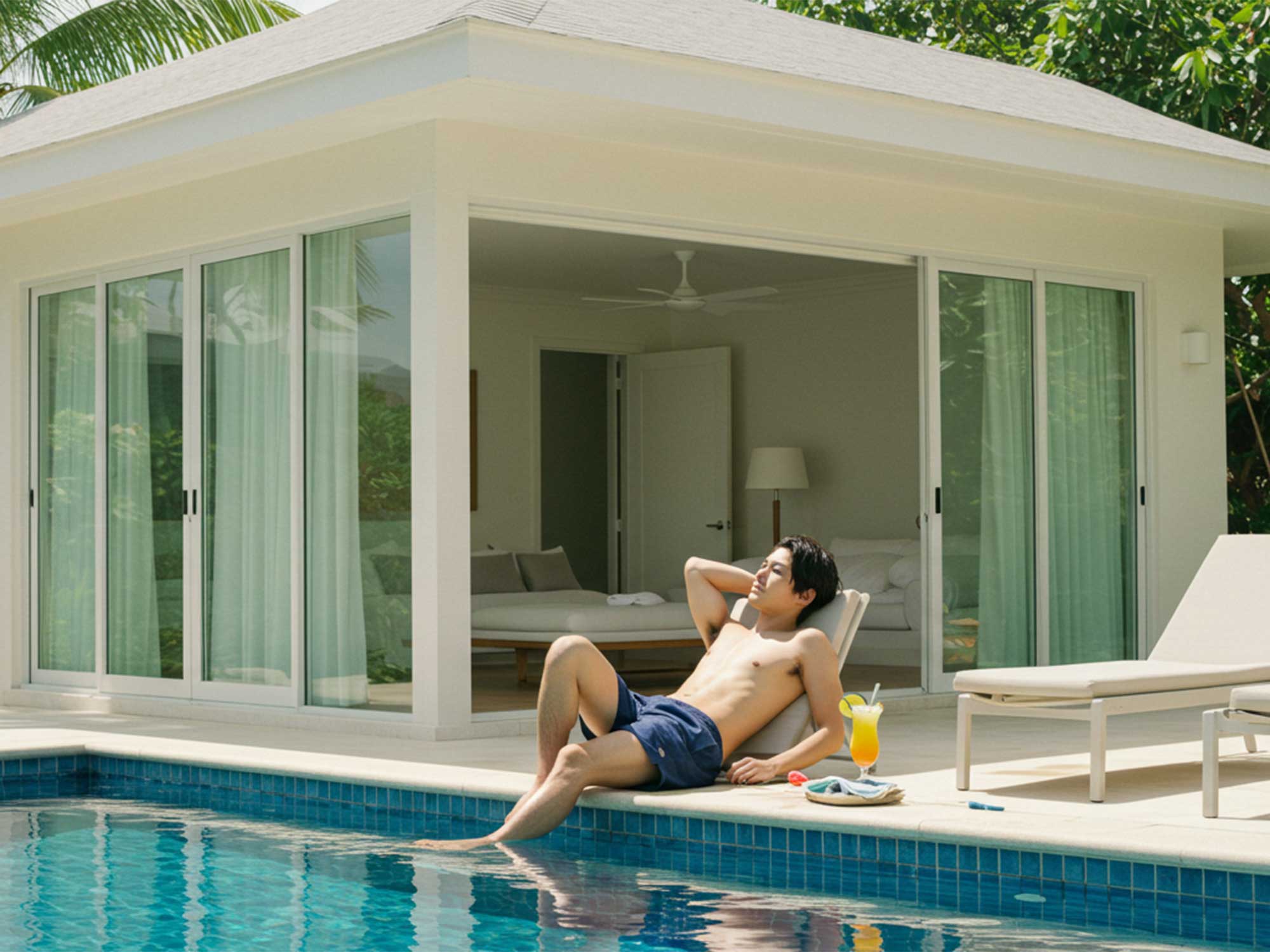 リゾートヴィラのプールサイドでリラックスする宿泊客