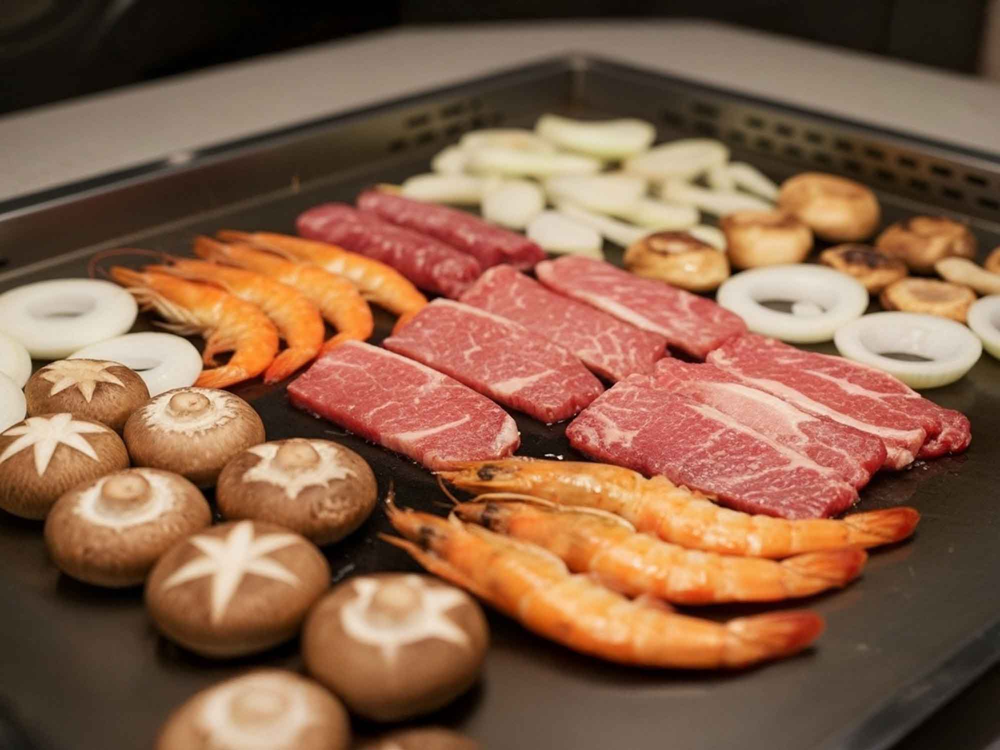 淡路島のヴィラで用意された新鮮な食材鉄板の上に牛肉エビ玉ねぎしいたけなどが並び豪華なバーベキューを楽しめる光景