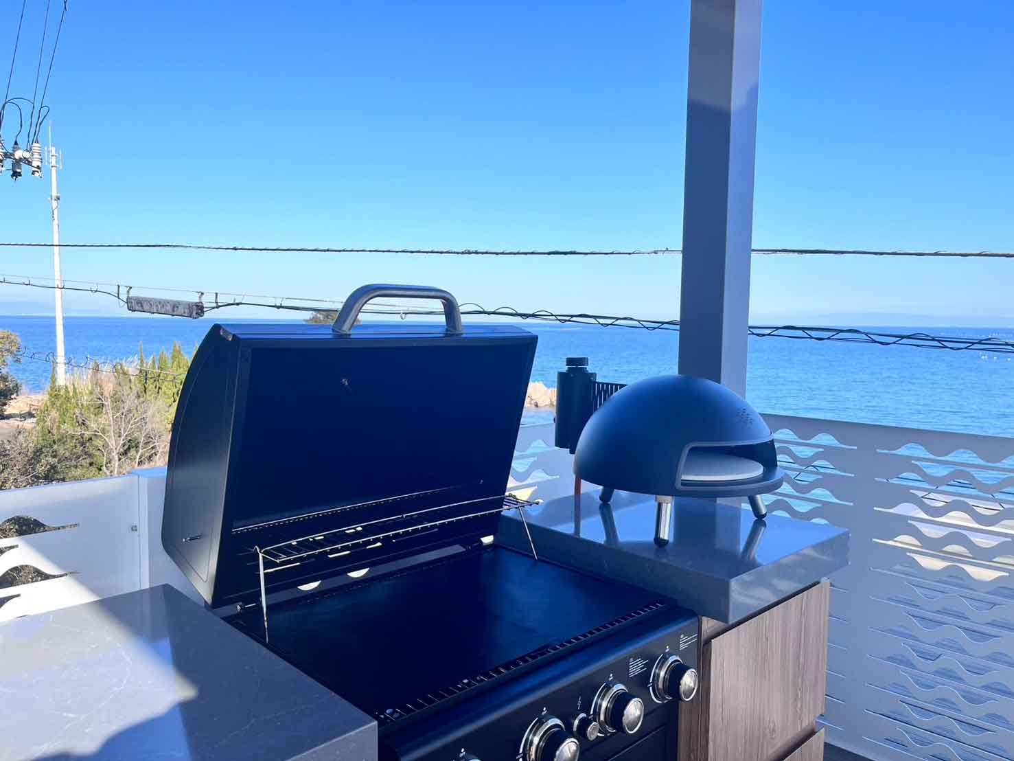 オーシャンビューのテラスに並ぶBBQグリルとピザ窯